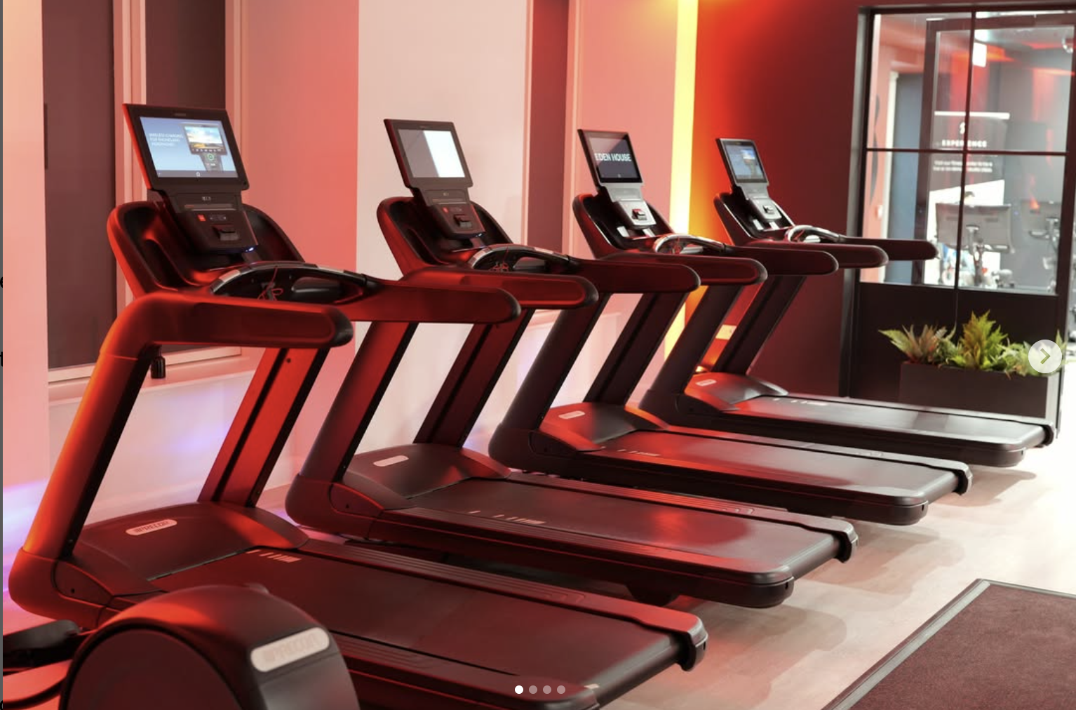 Row of treadmills in a gym with red lighting