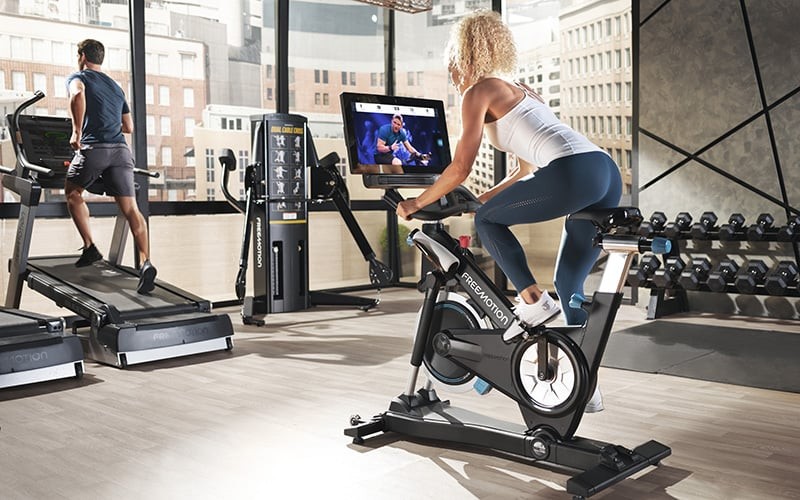 A woman rides a Free Motion stationary bike in a luxury condo gym. 