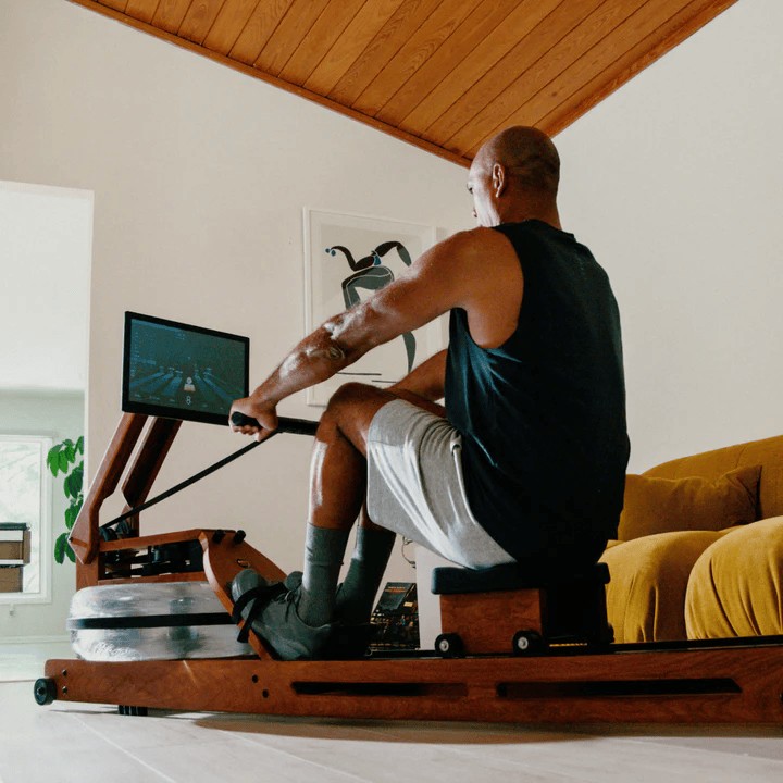 A man works out on an Ergatta rower in his living room.