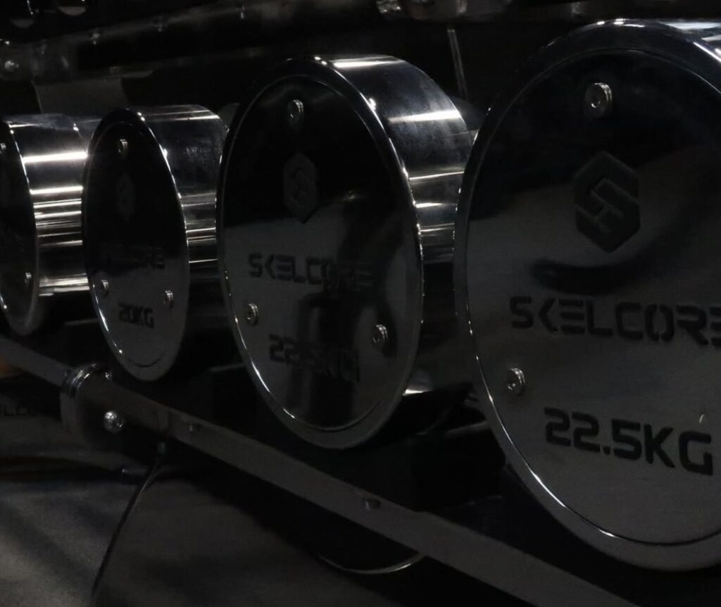 Closeup view of chrome Skelcore dumbbells in a row.