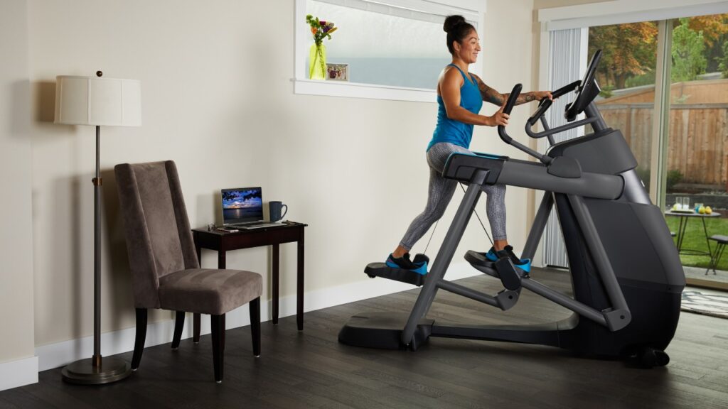 A woman works out on a Precore AMT Elliptical machine in her home gym.